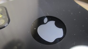увеличенное фото в районе логотипа с наклеенным защитным стекло на iphone 10